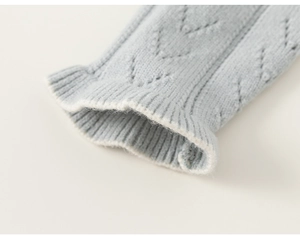 Nahaufnahme der hellblauen Strickjacke mit V-Muster und Rüschensaum am Ärmelbund