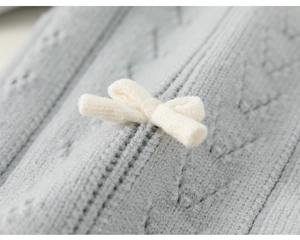 Detail der grauen Strickjacke für Mädchen mit Rautenmuster und cremefarbener Schleife