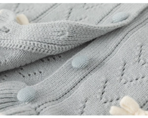 Nahaufnahme der hellblauen Strickjacke mit Rautenmuster und dekorativem Schleifendetail