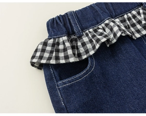 Nahaufnahme von tiefblauem Denim mit schwarz-weißem Karomuster-Volant am elastischen Bund