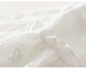 Dettaglio del ricamo sangallo bianco e del bordo a volant sulla gonna per bambine
