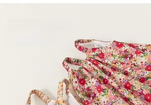 Detailed view of children floral dress featuring elastic straps and soft cotton texture