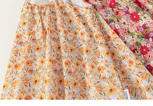 Detailed macro view of cotton floral fabrics in orange and pink with brand logo tag