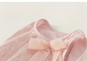 Détail de paillettes roses et d'un nœud en mousseline sur l'encolure de la robe de princesse