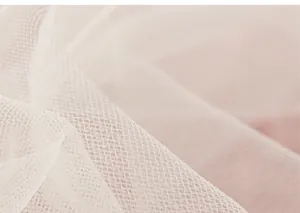 Vue macro des couches de tissu mesh rose pâle respirant sur une robe d'été fille