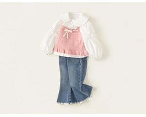 Detail of pink knit vest with bow and blue flared jeans with white wavy embroidery
