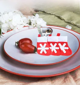 Three mini red and white snowflake Christmas stocking utensil holders for festive table setting