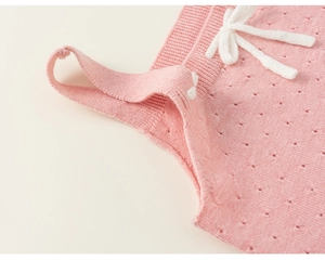 Dettaglio macro del gilet in maglia traforata rosa chiaro per bambina con fiocco