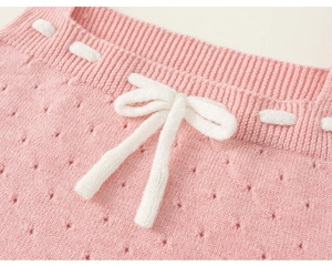 Dettaglio in maglia rosa con motivi traforati e un fiocco bianco intrecciato fine