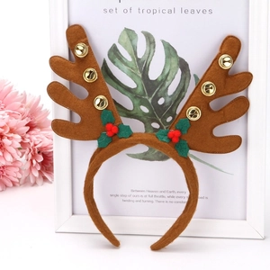 Close-up of brown reindeer antler headband with golden bells and holly berry details