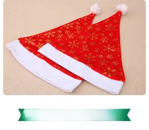 Detail view of two red Christmas hats with gold snowflake patterns and white fur trim