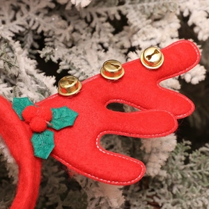 Detail of red felt reindeer antlers with golden bells and green holly leaves decoration