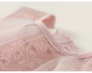 Détail de sequins roses et de tulle avec un bouton transparent sur la robe de princesse