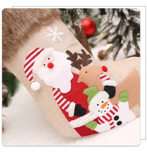 Détails d'appliqués 3D du Père Noël sur une chaussette de Noël en lin avec fausse fourrure