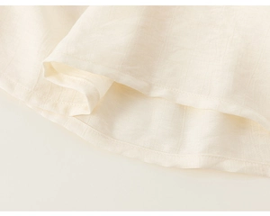 Detailaufnahme des cremefarbenen Saums mit vertikaler Textur an einem Mädchenkleid