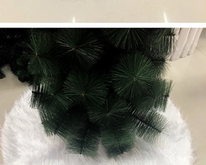 Detail shot of green pine needles on white plush faux fur Christmas tree skirt