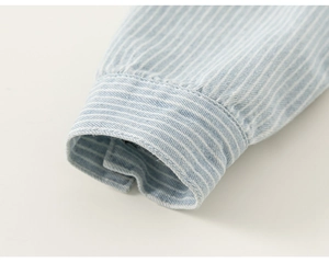 Detailed macro view of striped cuffs on a light blue cotton shirt for boys