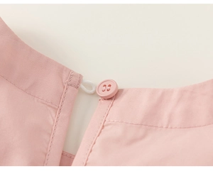 Detailaufnahme des rosa Baumwollkleid-Ausschnitts mit Knopfverschluss und Schlaufe