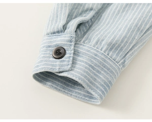 Macro shot of striped cotton shirt sleeve showing fine stitching and dark button detail