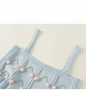 Close-up of light blue knit vest with pink floral 3D decor and green embroidery