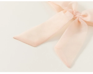 Gros plan détaillé du nœud en tulle rose clair avec texture délicate sur la robe de fille