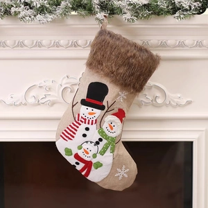 Chaussette de Noël en lin avec broderie bonhomme de neige suspendue sur une cheminée blanche
