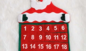 Detail of Santa Claus felt advent calendar with numbered pockets on white plush background