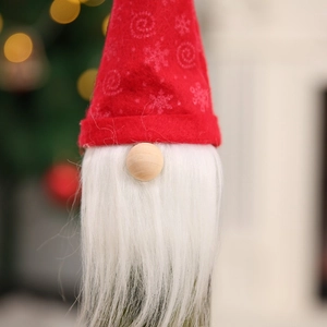 Detail shot of a plush Christmas gnome bottle topper with white faux fur beard and red hat
