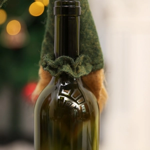 Close-up of a festive forest green felt Christmas wine bottle cover with brown faux fur trim