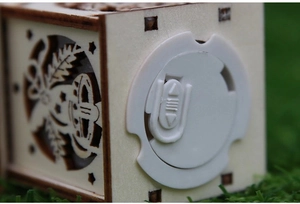 Close-up of laser-cut wood pattern and white power switch on the Christmas house ornament