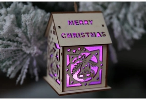 Macro view of a wooden light-up Christmas house with purple LED and Merry Christmas carving