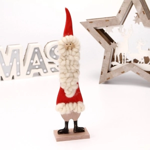 Detail of handcrafted wooden Santa figurine with red hat and white felt beard on base