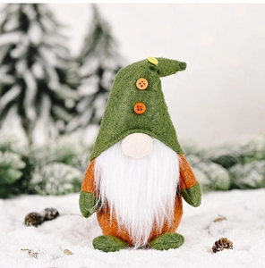 Macro view of handmade Christmas gnome with green felt hat on winter snow background