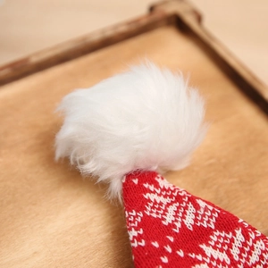 Close-up of knitted red Christmas hat with white snowflake patterns and plush pom-pom