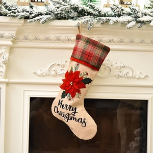 Linen Christmas stocking with red floral decor and plaid trim on a fireplace