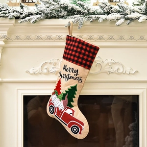 Linen Christmas stocking with red truck and gnome design hanging on a snowy mantel