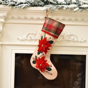 Linen Christmas stocking with red poinsettia flowers hanging on a white fireplace