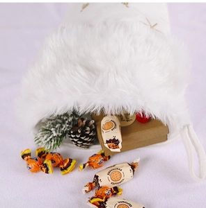 Gros plan sur une chaussette de Noël en peluche blanche remplie de cadeaux et de pins