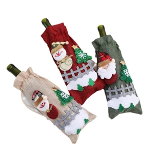 Three linen Christmas wine bottle covers featuring Santa, snowman, and tree decorations