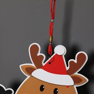 Close-up of a Christmas reindeer paper pendant with a red woven cord and metal buckle