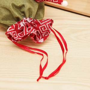 Detail of burlap Christmas gift bag with red ribbon drawstring and olive green fabric