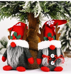 Detailed view of two Christmas gnomes with antlers and bells under a snowy pine tree