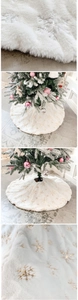 Close-up of plush white Christmas tree skirt with embroidered gold and silver sequins