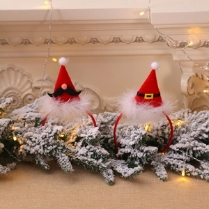 Red Christmas hat headbands with white fur trim and bells set on festive cedar branches