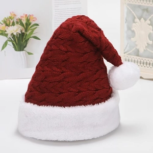 Thick knit red Christmas hat with white pompom and cable texture on a cozy background