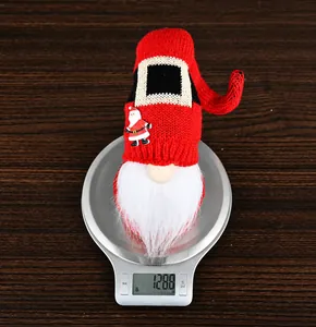 Close-up of a red knitted Christmas gnome on a scale showing a weight of 128.8g