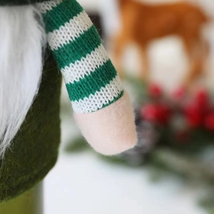 Detail of Christmas gnome bottle cover featuring green felt body and white faux fur beard