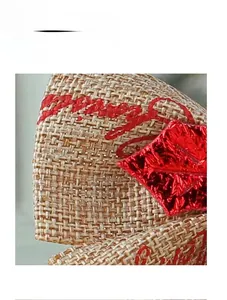 Macro shot of linen bowknot with Merry Christmas red embroidery and glossy leaves