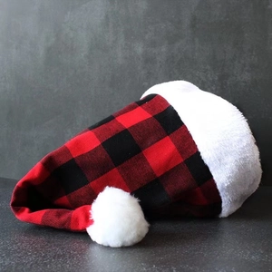 Classic red and black plaid Christmas hat with white plush trim on dark stone background