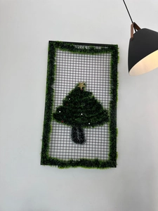 Detail of Christmas tree wall hanging decor with green tinsel and gold star on black mesh